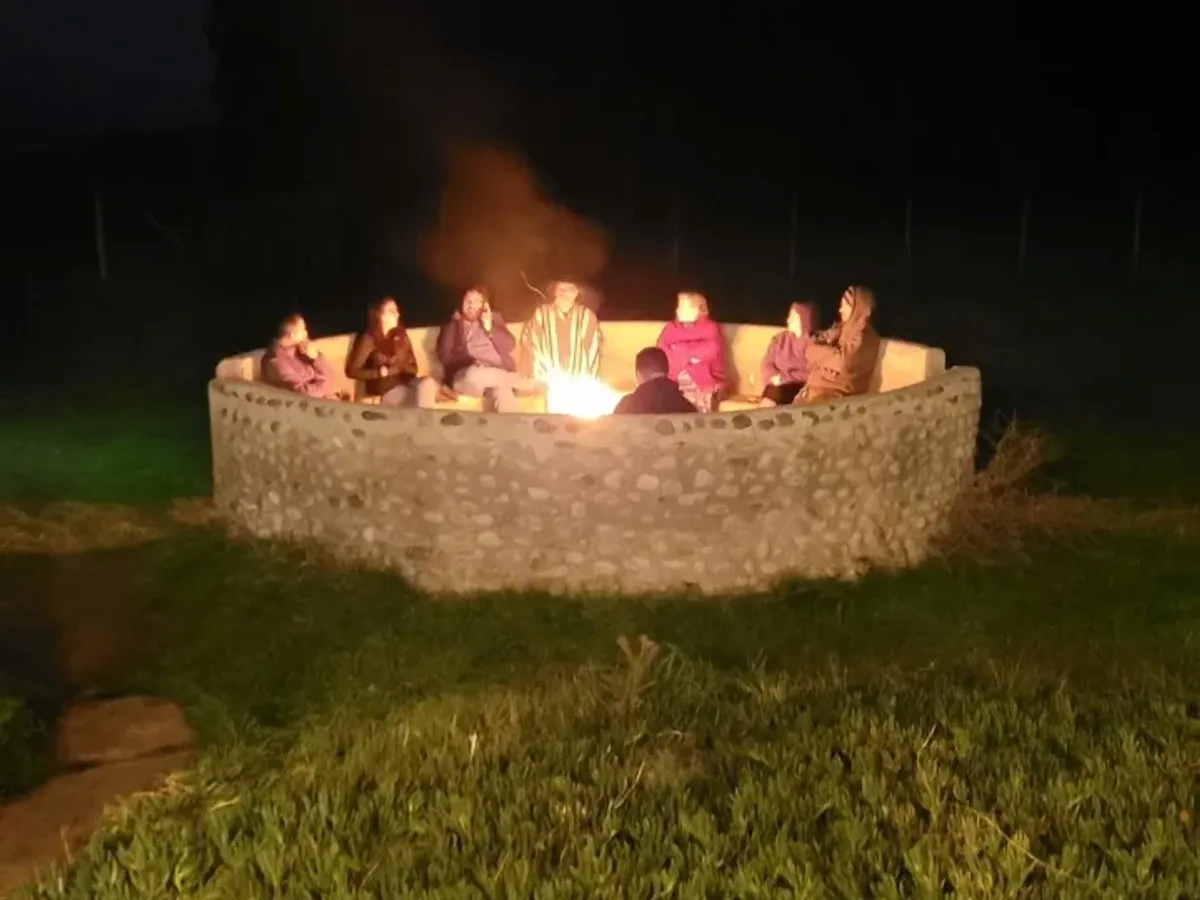 Fogón de piedra de Lomatanzas de noche con un grupo alrededor del fuego