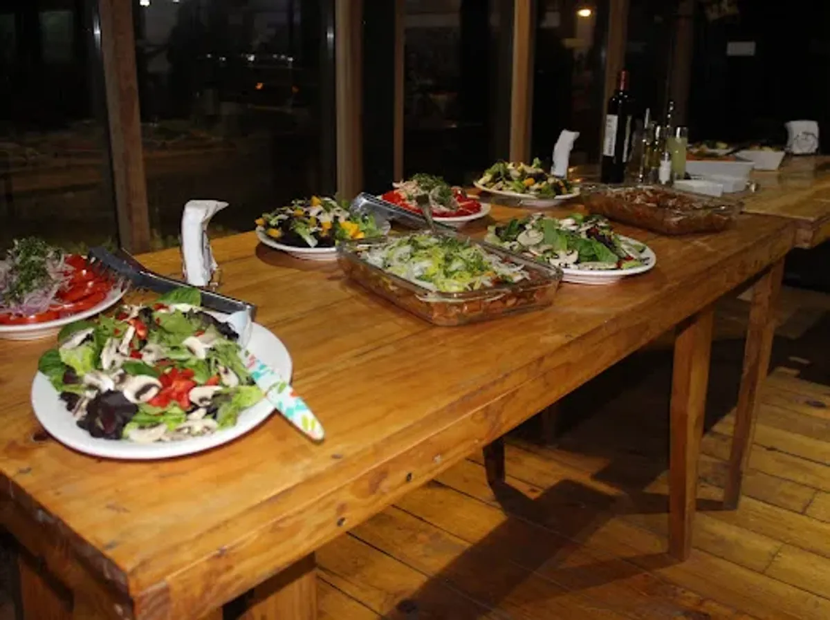 Buffet de ensaladas sobre la mesa de madera del quincho en un matrimonio