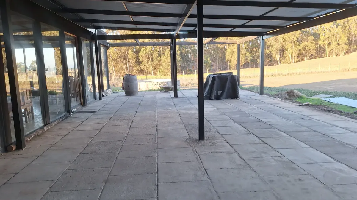 Terraza techada del quincho con piso de piedra y vista al bosque